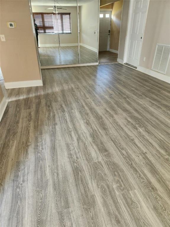 A room with light wood-look flooring, mirrored closet doors, and a white interior door — 6890 VERSAILLES N UNIT 10, PINELLAS PARK, FL