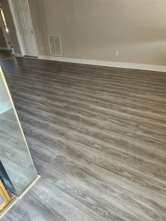 A room with light-colored walls and gray wood-look laminate flooring — 6890 VERSAILLES N UNIT 10, PINELLAS PARK, FL