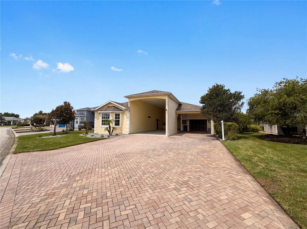 A single-story house with a paved driveway, a large carport, and light yellow siding — 376 TRAVELERS DRIVE, POLK CITY, FL
