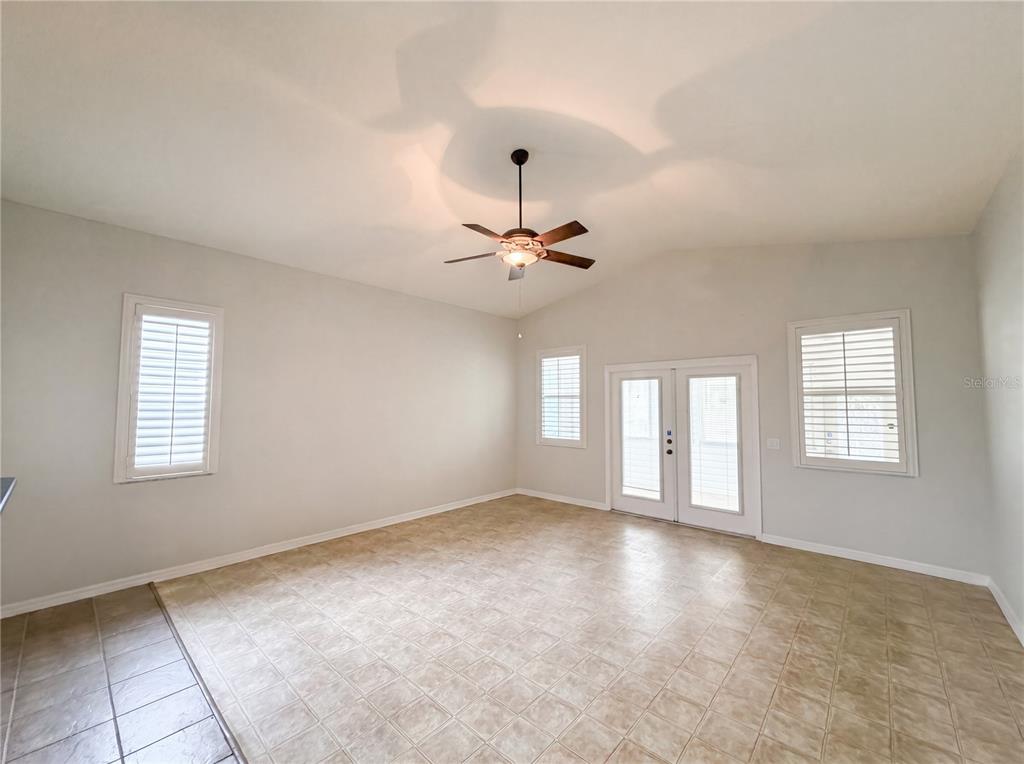 A spacious room with light-colored walls, tile flooring, a ceiling fan, and glass French doors — 376 TRAVELERS DRIVE, POLK CITY, FL
