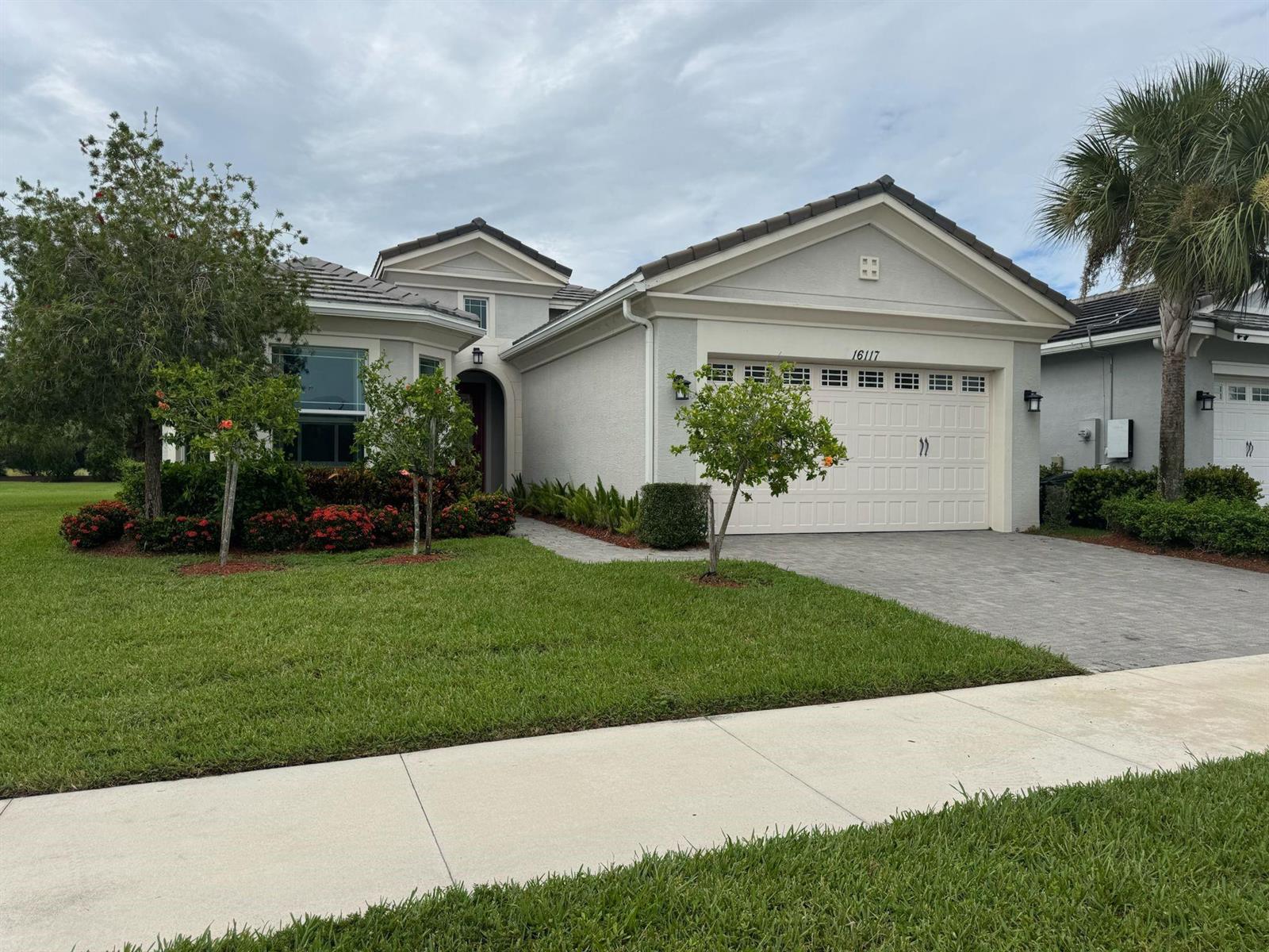A single-story house with a beige stucco exterior, a two-car garage, and a paved driveway — 16117 Whippoorwill Circle, FL 33470, FL