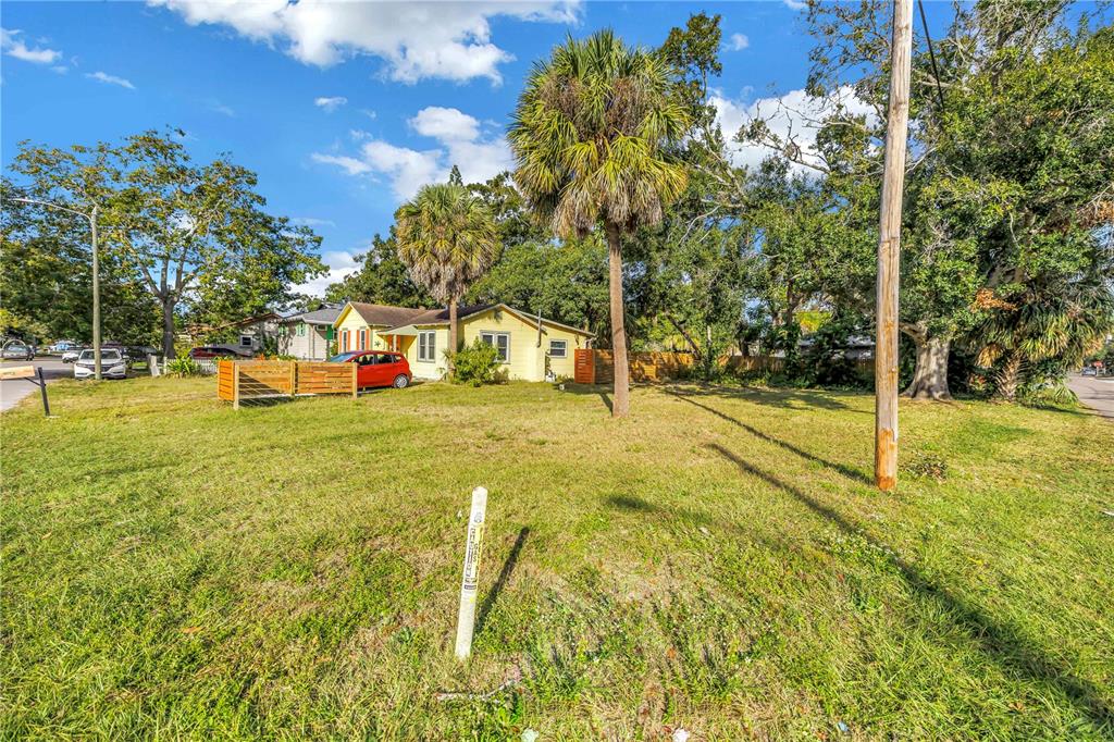 A yellow house sits on a grassy lot with palm trees and a wooden fence — PRESTON AVENUE S, GULFPORT, FL
