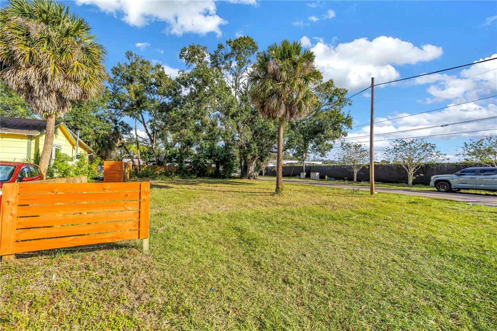 A grassy vacant lot features a wooden privacy screen and several palm trees — PRESTON AVENUE S, GULFPORT, FL