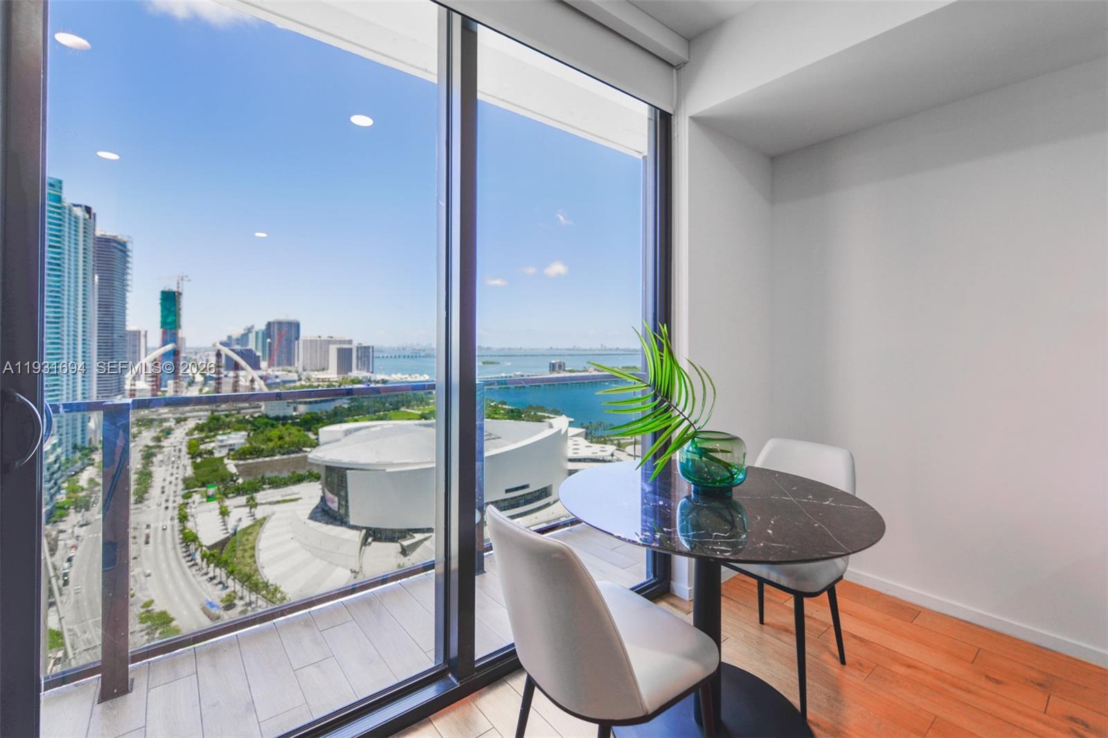A dining area with a marble table and two chairs overlooks a city skyline view — 398 NE 5th St # 2407, Miami FL 33132, MIAMI, FL