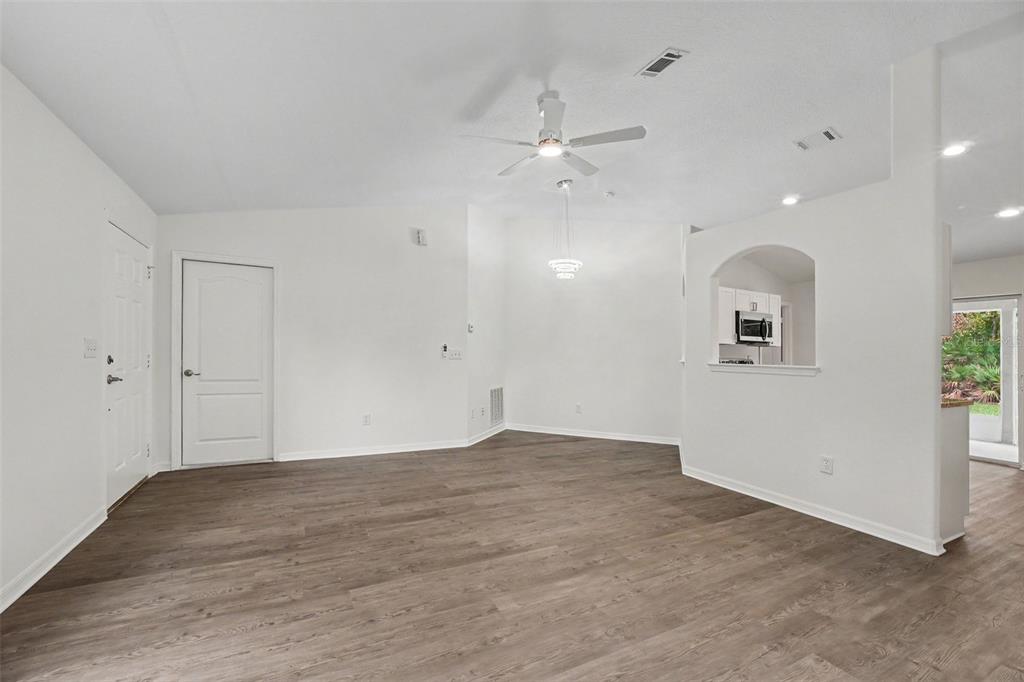 A bright, empty living room features white walls, wood-look flooring, and a ceiling fan — 30 PIERMOUNT LANE, PALM COAST, FL