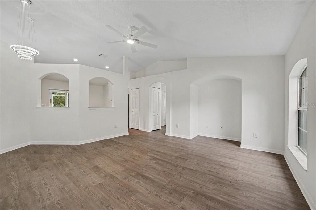 A bright, empty living room features white walls, vaulted ceilings, and wood-look vinyl flooring — 30 PIERMOUNT LANE, PALM COAST, FL
