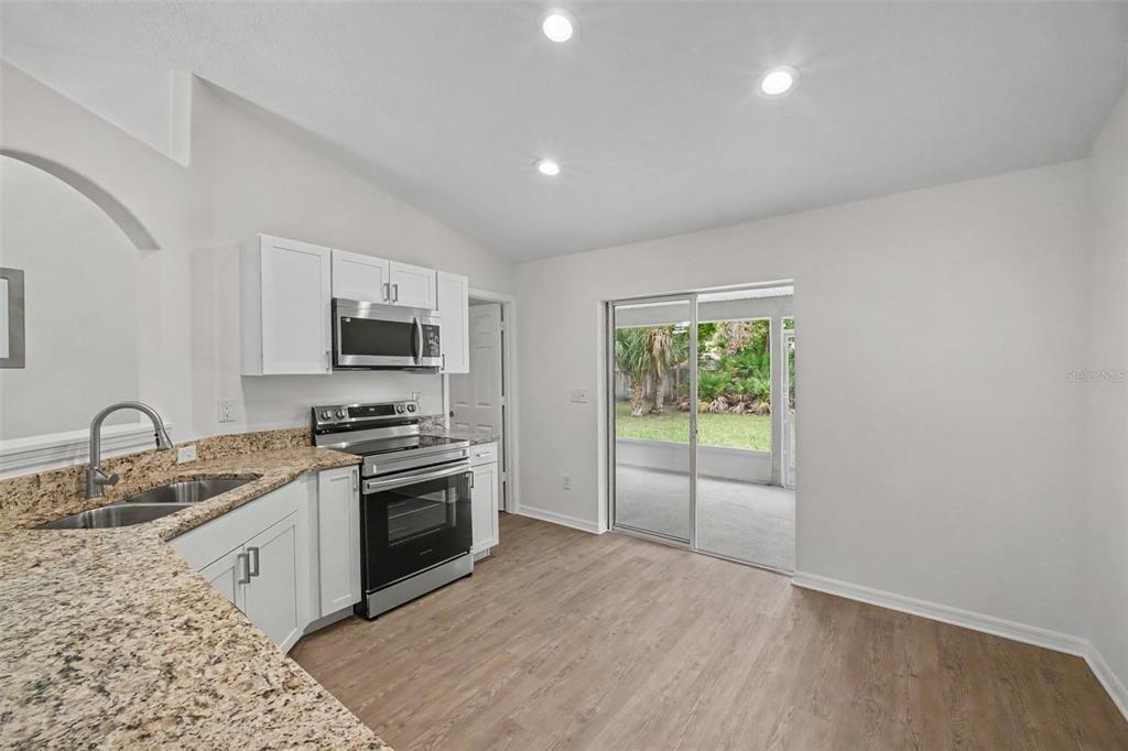 A kitchen with white cabinets, granite countertops, stainless steel appliances, and a sliding glass door — 30 PIERMOUNT LANE, PALM COAST, FL