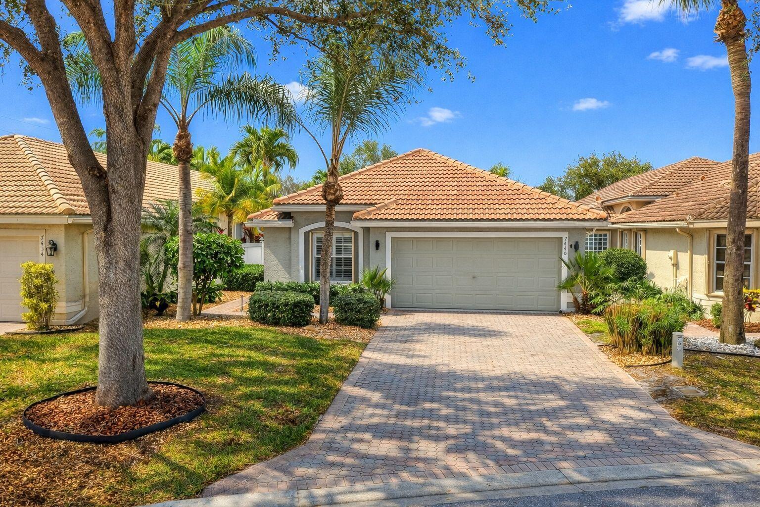 A single-story house with a tiled roof, a paved driveway, and palm trees in front — 7440 W Mercada Way, Delray Beach FL 33446, DELRAY BEACH, FL