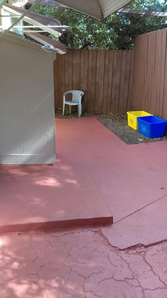 A small, red-painted concrete patio features a white plastic chair and two storage bins — 11810 Ellison Wilson Road, FL 33408, FL