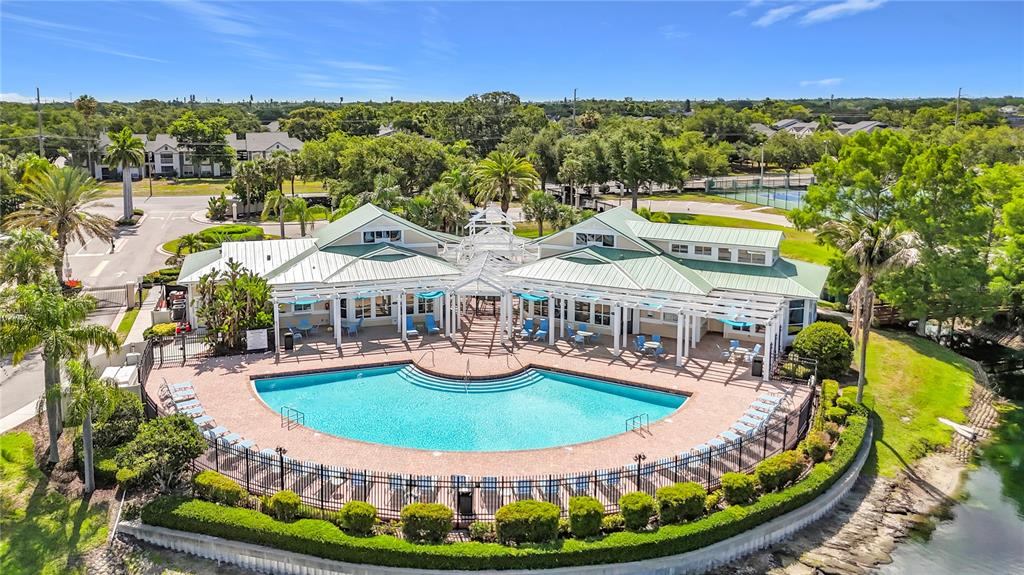 An aerial view of a community clubhouse with a curved swimming pool and surrounding landscaping — 4802 51ST STREET W UNIT 1116, BRADENTON, FL