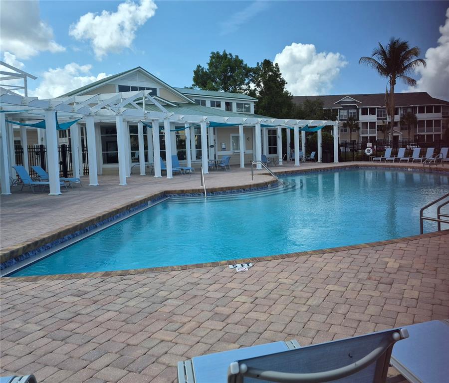 A swimming pool with a paved deck and a pergola-covered patio area — 4802 51ST STREET W UNIT 1116, BRADENTON, FL