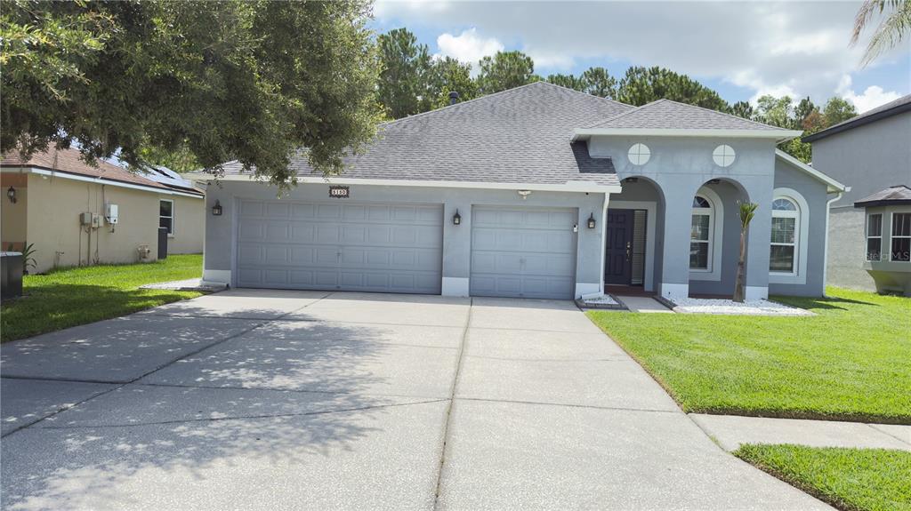 A single-story gray house with a two-car garage and a green lawn — 5150 VILLAGEBROOK DRIVE, WESLEY CHAPEL, FL
