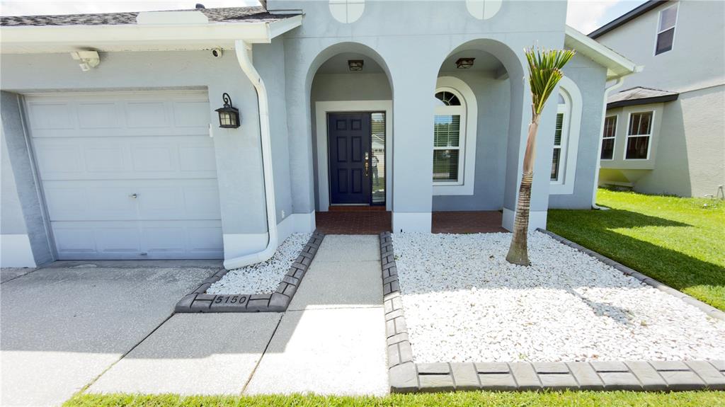 An entryway with tiled flooring, a white front door, and two arched windows — 5150 VILLAGEBROOK DRIVE, WESLEY CHAPEL, FL