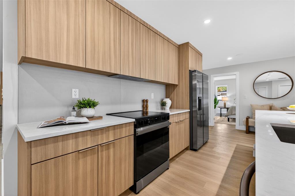 A modern kitchen features light wood cabinets, white countertops, and stainless steel appliances — 6649 PINELLAS POINT DRIVE S, ST PETERSBURG, FL