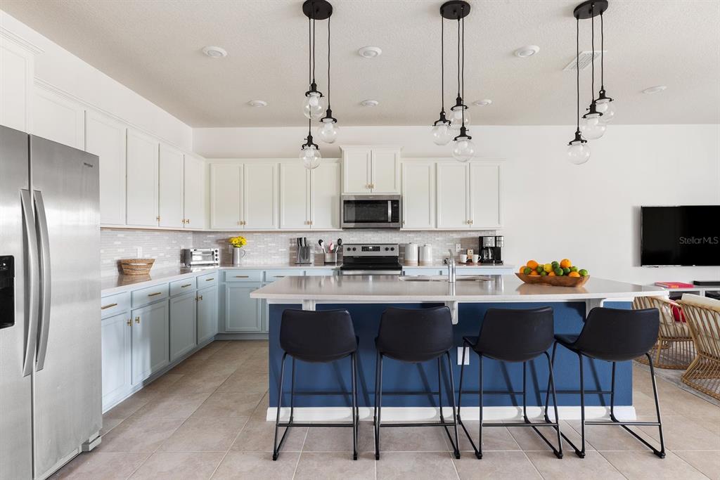 A kitchen features white upper cabinets, light blue lower cabinets, a dark blue island, and barstools — 2320 LELANI CIRCLE, DAVENPORT, FL