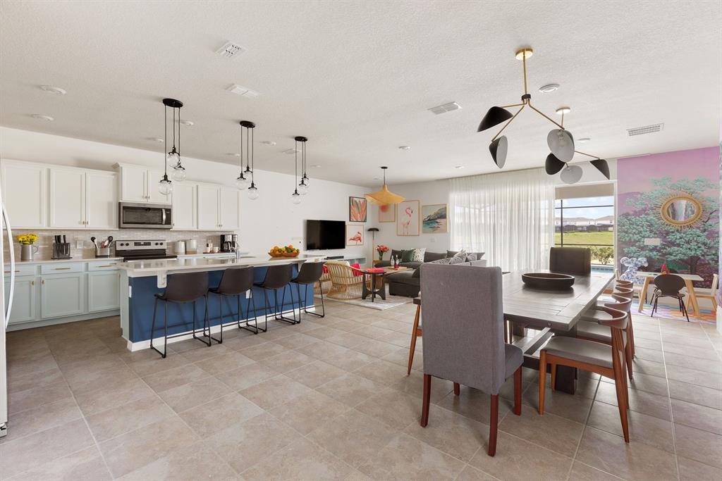 An open-concept kitchen, dining area, and living room featuring a blue island and tile flooring — 2320 LELANI CIRCLE, DAVENPORT, FL