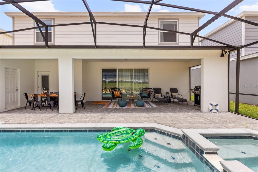 A covered patio with outdoor furniture overlooks a swimming pool and a hot tub — 2320 LELANI CIRCLE, DAVENPORT, FL