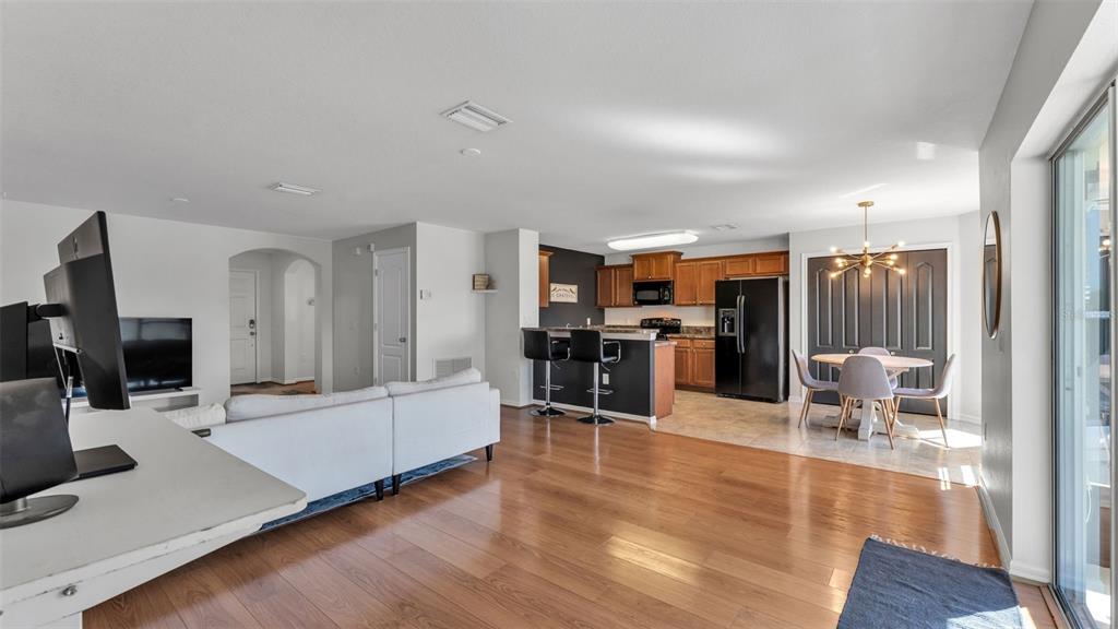 An open-concept living area features wood flooring, a kitchen with dark cabinets, and dining space — 2447 LADOGA DRIVE, LAKELAND, FL