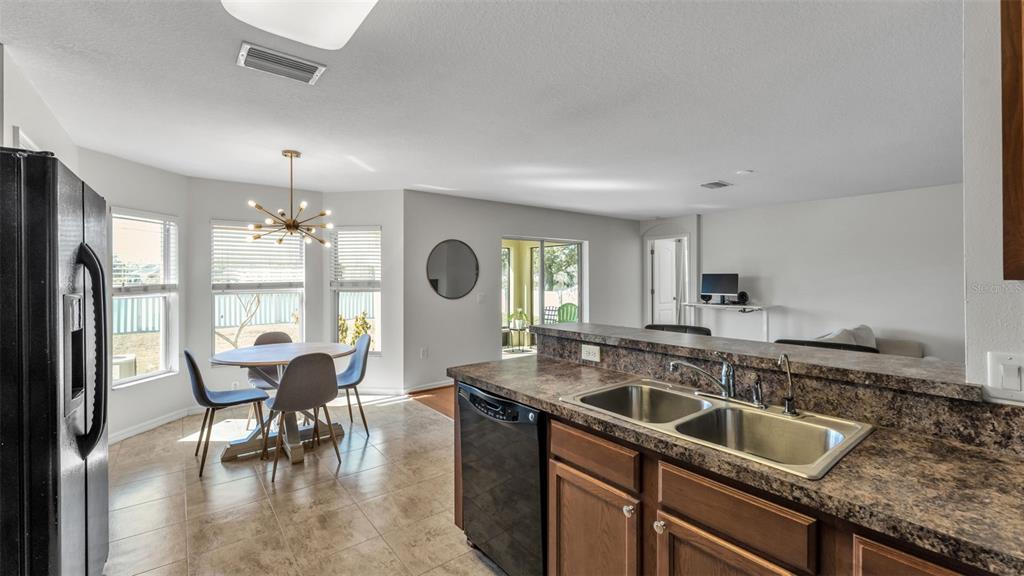 A kitchen with dark countertops and cabinets overlooks a dining area with a modern chandelier — 2447 LADOGA DRIVE, LAKELAND, FL