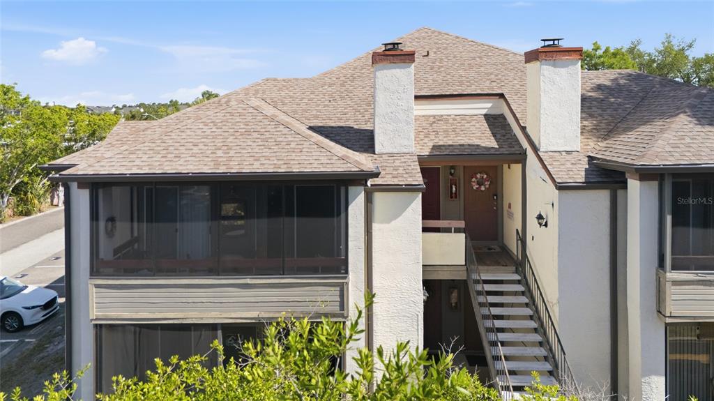 An exterior view of a two-story building with a screened balcony and outdoor staircase — 10265 GANDY BOULEVARD N UNIT 1806, ST PETERSBURG, FL