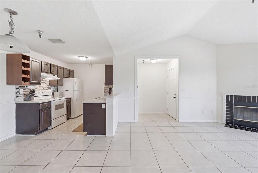 A kitchen with dark cabinets and white appliances opens into a tiled living area — 10265 GANDY BOULEVARD N UNIT 1806, ST PETERSBURG, FL
