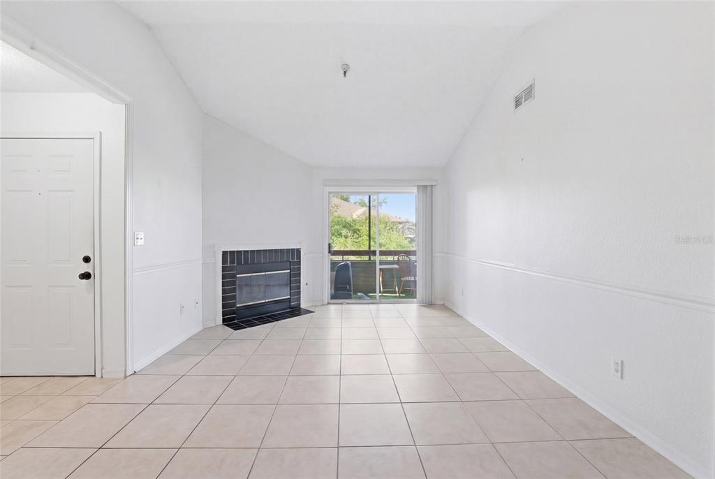 A living room with white walls, tile flooring, a fireplace, and a sliding glass door — 10265 GANDY BOULEVARD N UNIT 1806, ST PETERSBURG, FL