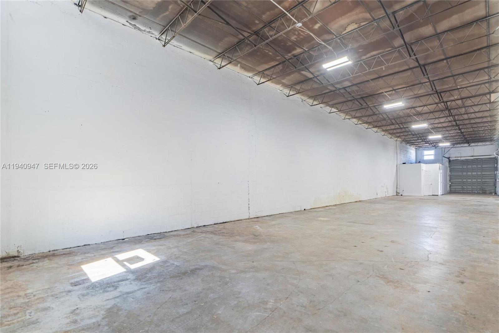 An empty industrial warehouse space features a concrete floor, white block walls, and exposed ceiling — 1676 W 31st Pl, Hialeah FL 33012, HIALEAH, FL