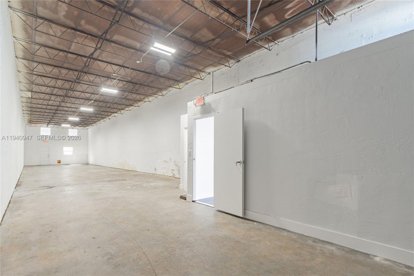 An empty industrial warehouse space features white walls, a concrete floor, and exposed ceiling trusses — 1676 W 31st Pl, Hialeah FL 33012, HIALEAH, FL