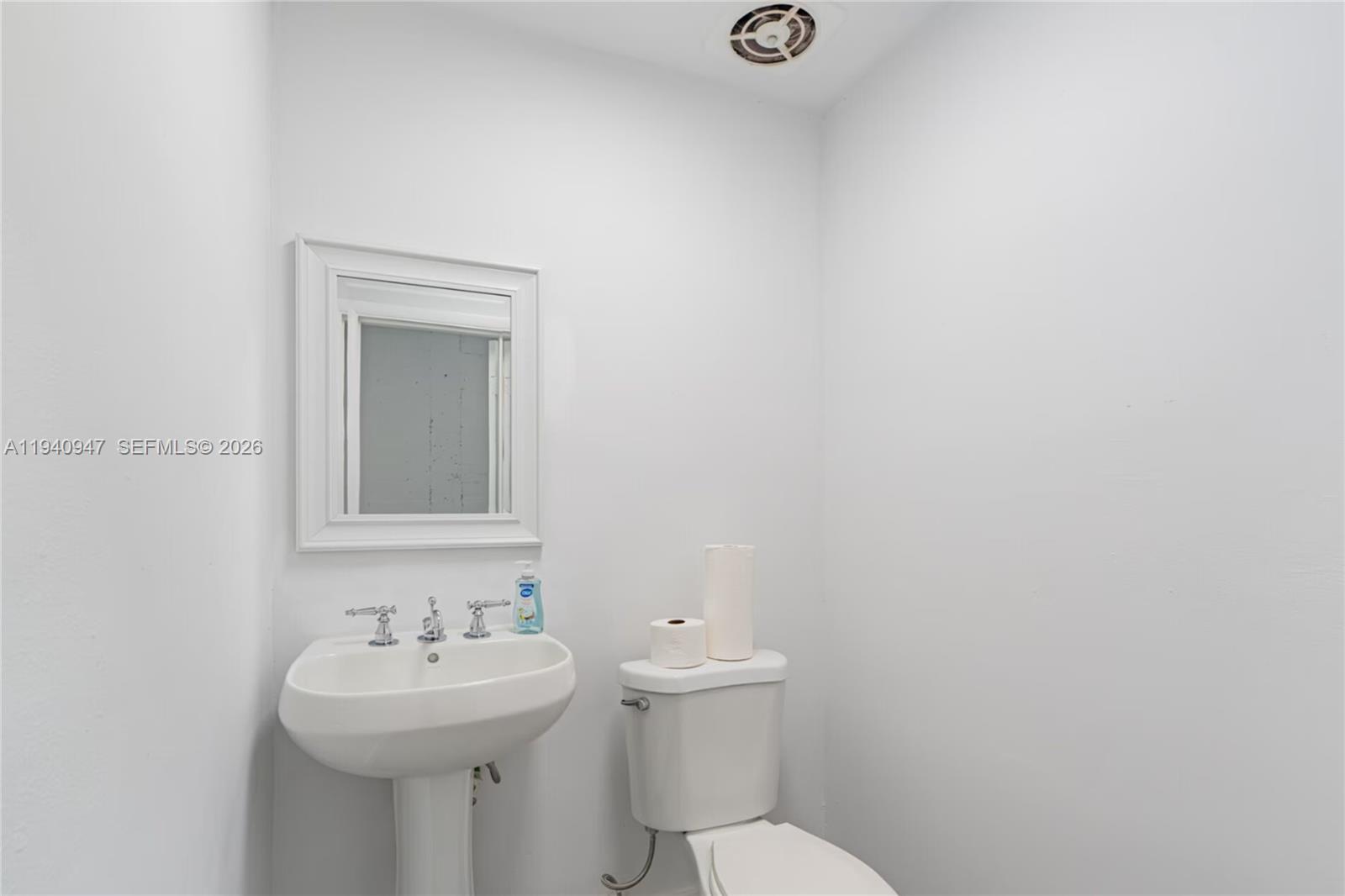 A small bathroom features a white pedestal sink, a toilet, and a wall-mounted mirror — 1676 W 31st Pl, Hialeah FL 33012, HIALEAH, FL