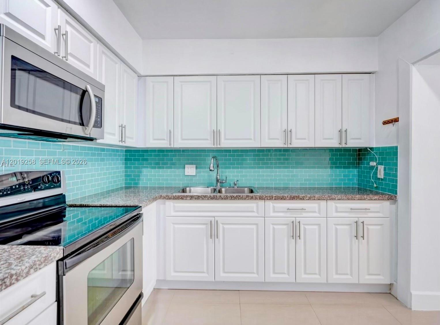 A kitchen features white cabinets, stainless steel appliances, granite countertops, and a teal subway-tile backsplash — 9494 SW 39th St, Miami FL 33165, MIAMI, FL