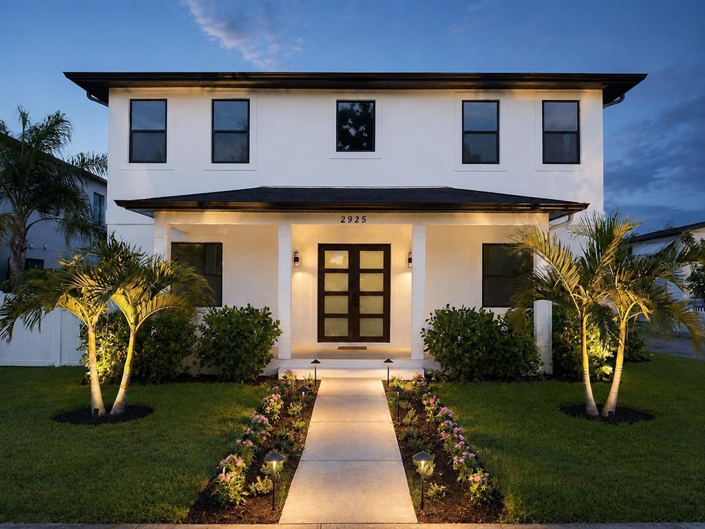 A two-story white house with a dark roof, front porch, and illuminated walkway at dusk — 2925 13TH STREET N, ST PETERSBURG, FL