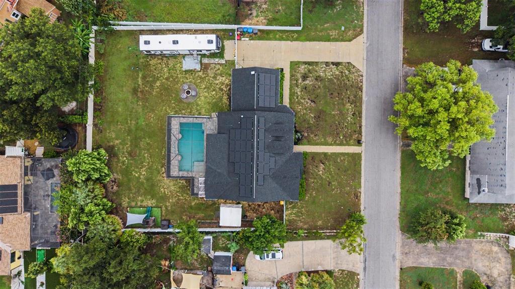 An aerial view shows a house with solar panels, a pool, and a large backyard — 606 ROYAL CREST DRIVE, BRANDON, FL
