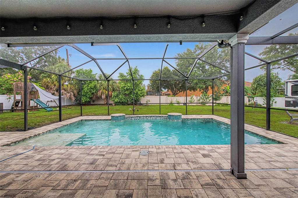 A screened-in patio features a rectangular swimming pool with two small fountains and paver decking — 606 ROYAL CREST DRIVE, BRANDON, FL