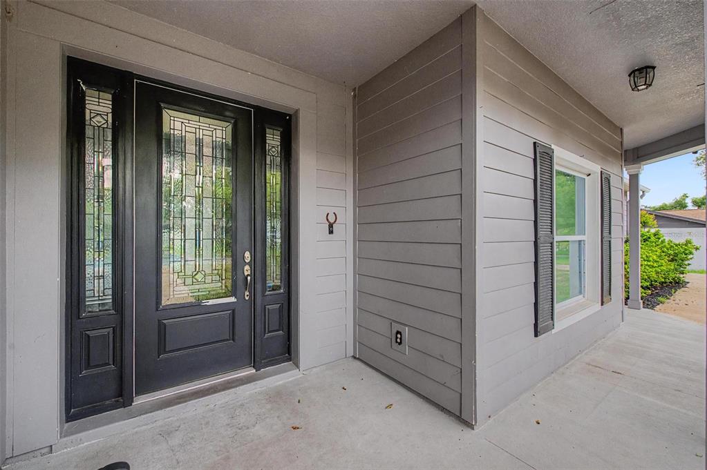 A covered front porch features a black front door with sidelights and gray horizontal siding — 606 ROYAL CREST DRIVE, BRANDON, FL