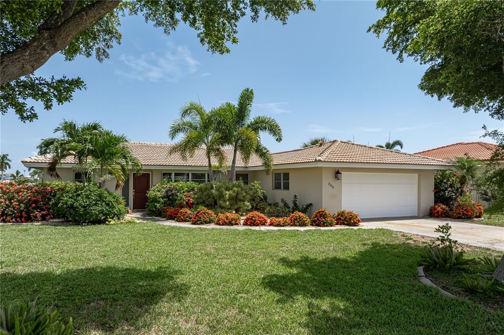 A single-story house with a tiled roof, white garage, and landscaping under a blue sky — 2208 CASSINO COURT, PUNTA GORDA, FL