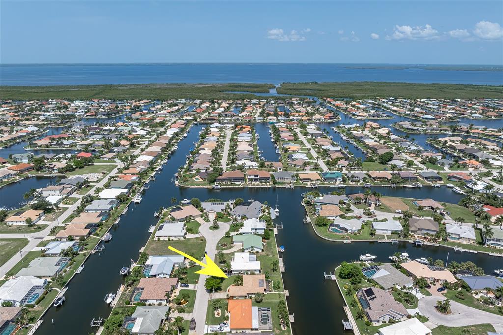 An aerial view shows a waterfront residential neighborhood with a yellow arrow pointing to a house — 2208 CASSINO COURT, PUNTA GORDA, FL
