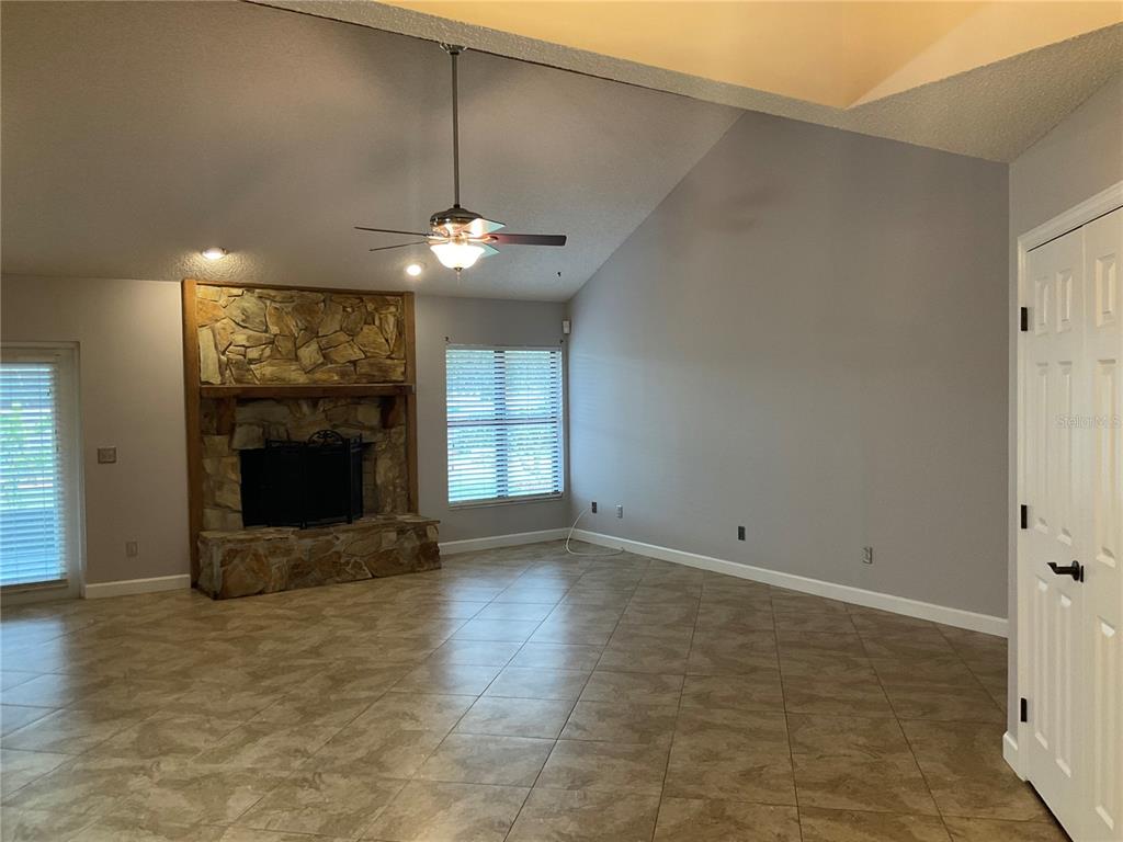 A living room features a stone fireplace, tile flooring, and a vaulted ceiling with fan — 4273 STAFFORD DRIVE, WINTER HAVEN, FL