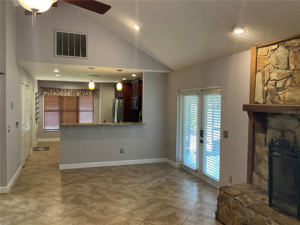 A living room with tile floors, a stone fireplace, and an open kitchen with a bar — 4273 STAFFORD DRIVE, WINTER HAVEN, FL