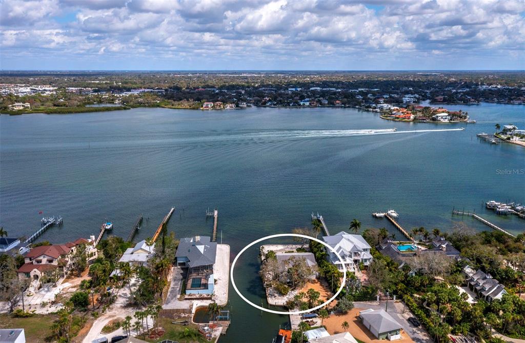 An aerial view shows a waterfront house on a small peninsula surrounded by a canal — 1267 STARBOARD LANE, SARASOTA, FL