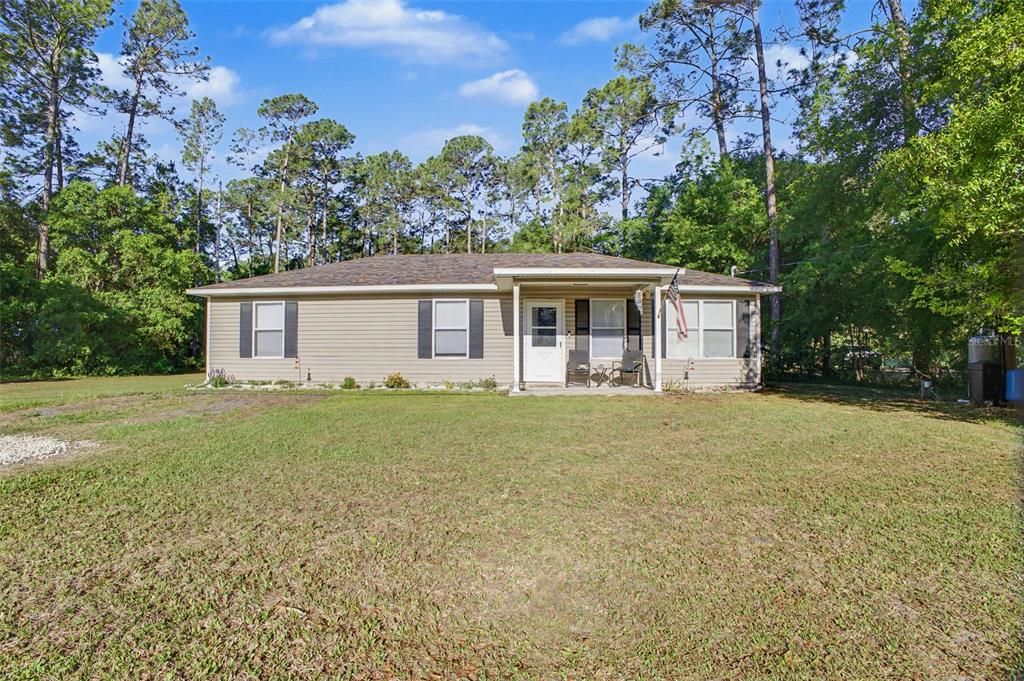 A single-story house with tan siding and a covered front porch sits on a lawn — 1886 LAUREL AVENUE, BUNNELL, FL