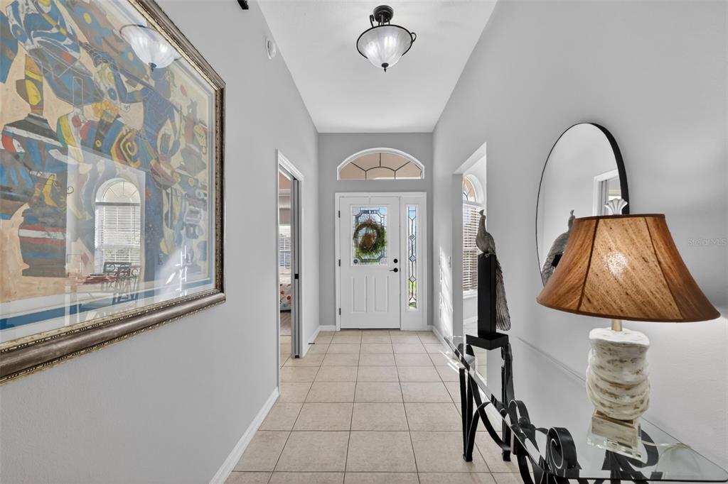 A bright entryway features tile flooring, a white front door, and a console table — 17325 SE 73RD PARK GLEN COURT, THE VILLAGES, FL