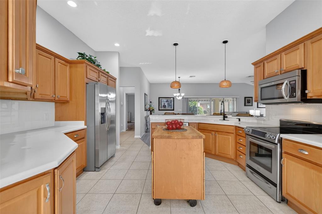 A kitchen with light wood cabinets, stainless steel appliances, a center island, and tile flooring — 17325 SE 73RD PARK GLEN COURT, THE VILLAGES, FL