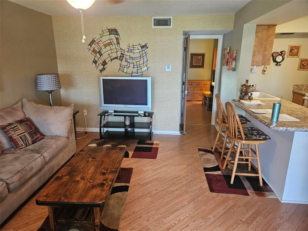 A living room features a sofa, coffee table, television, and a breakfast bar with stools — 303 47TH AVENUE DR W UNIT 352, BRADENTON, FL