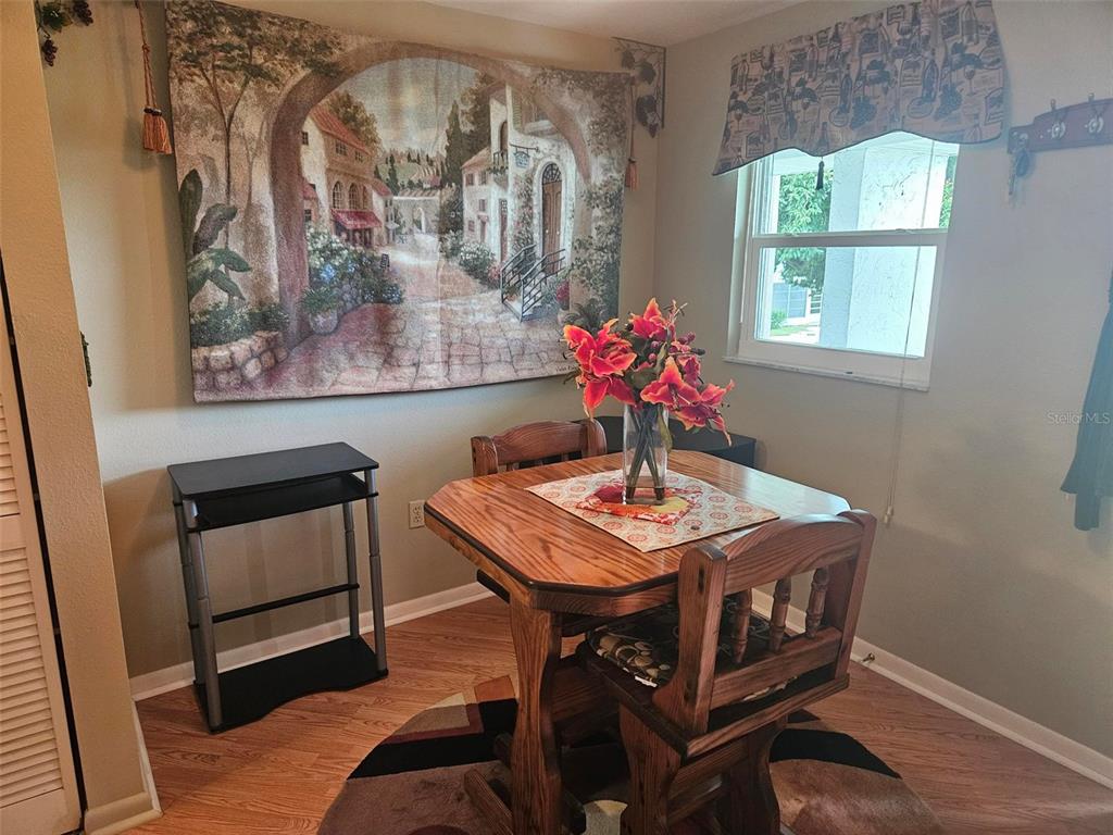 A dining area features a wooden table, two chairs, a wall tapestry, and a small desk — 303 47TH AVENUE DR W UNIT 352, BRADENTON, FL