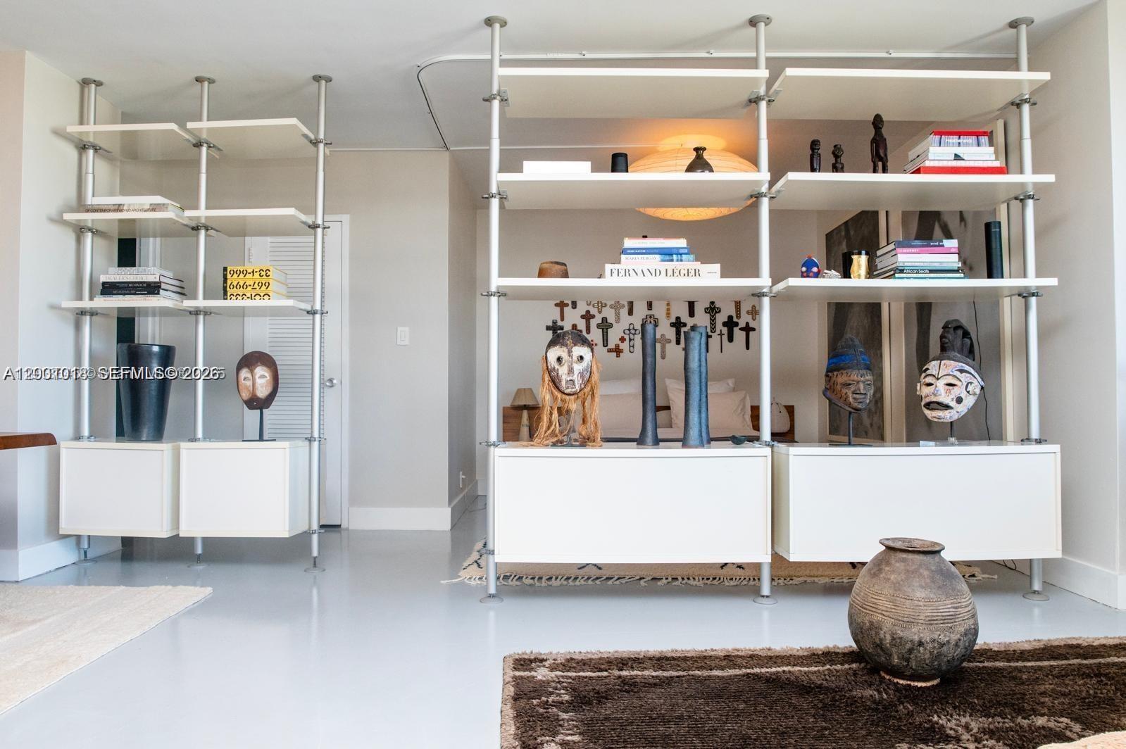 A room features floor-to-ceiling metal shelving units displaying art and books on white cabinets — 1000 West Ave # 1504, Miami Beach FL 33139, MIAMI BEACH, FL