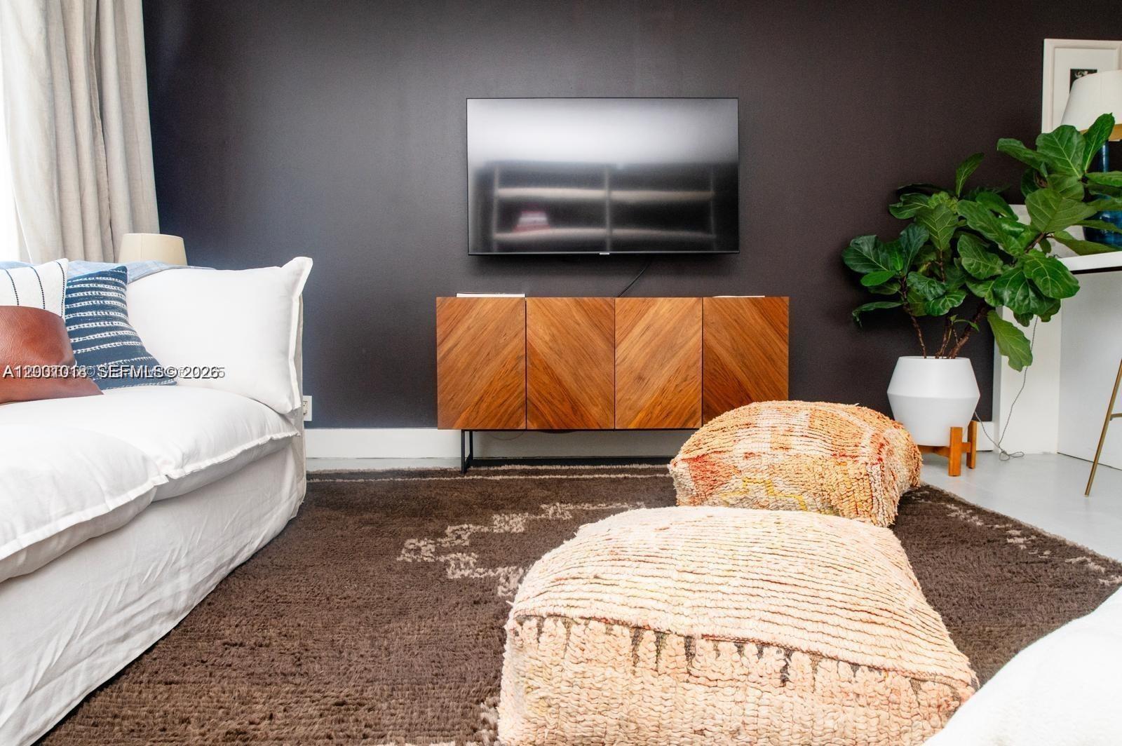 A living room features a dark accent wall, a wall-mounted television, and a wooden console — 1000 West Ave # 1504, Miami Beach FL 33139, MIAMI BEACH, FL