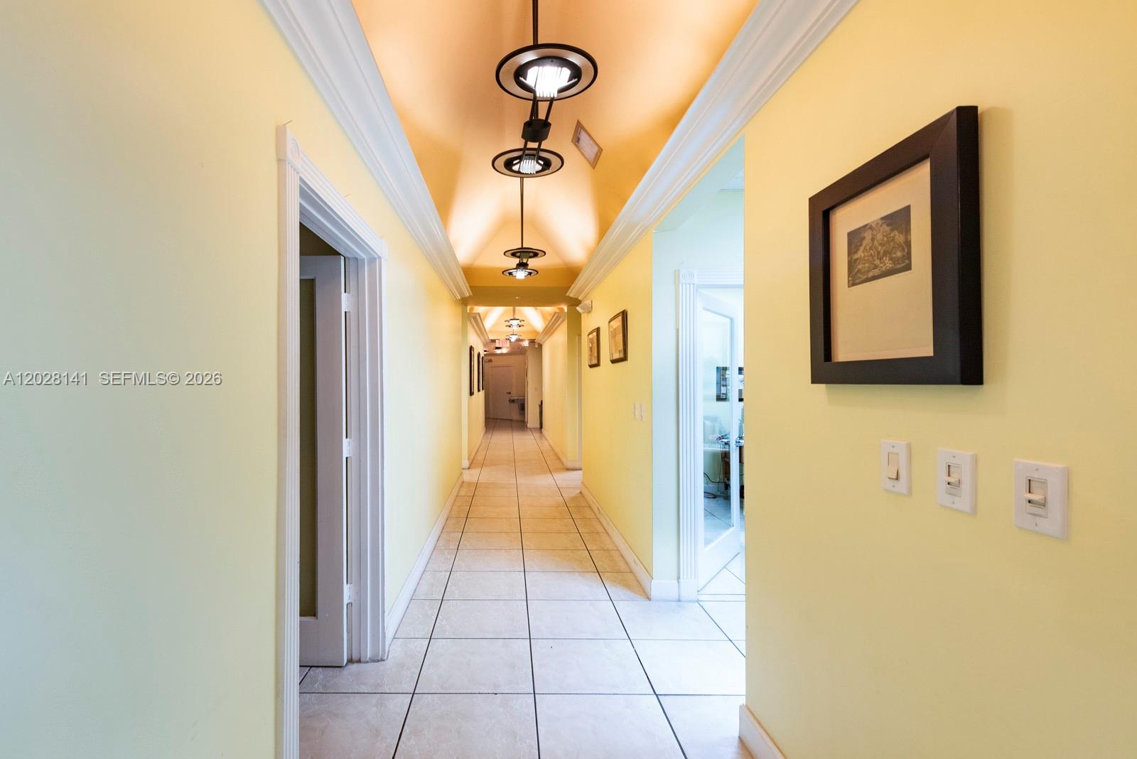 A long hallway features yellow walls, tile flooring, and a vaulted ceiling with pendant lighting — 10200 NW 25th St # A105, Doral FL 33172, DORAL, FL