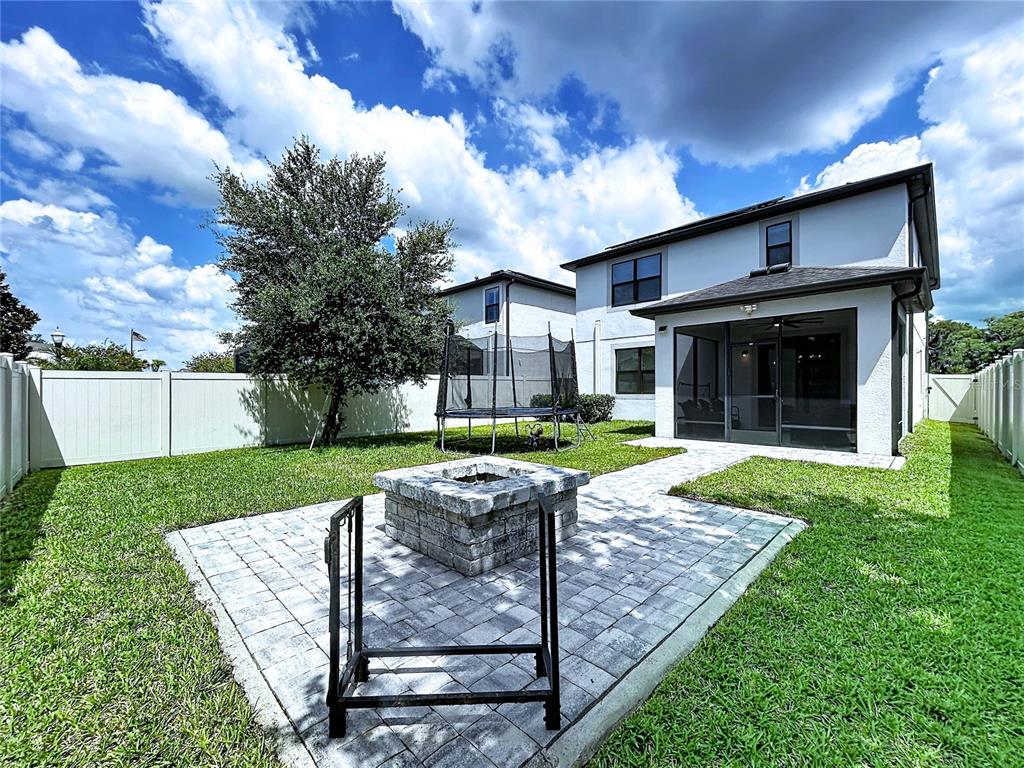A backyard features a stone fire pit, a paved patio, a trampoline, and a screened porch — 19219 LEONARD ROAD, LUTZ, FL