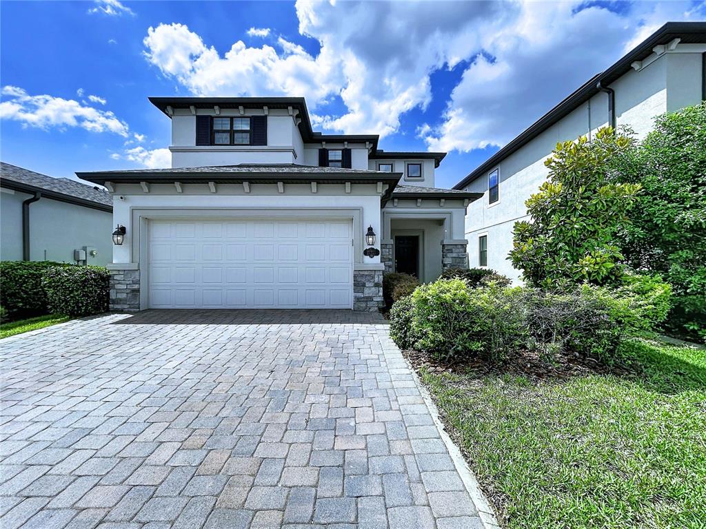 A two-story house with a paved driveway, white garage door, and stone accents — 19219 LEONARD ROAD, LUTZ, FL