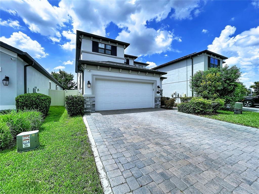 A two-story house with a white stucco facade, a stone base, and a paved driveway — 19219 LEONARD ROAD, LUTZ, FL